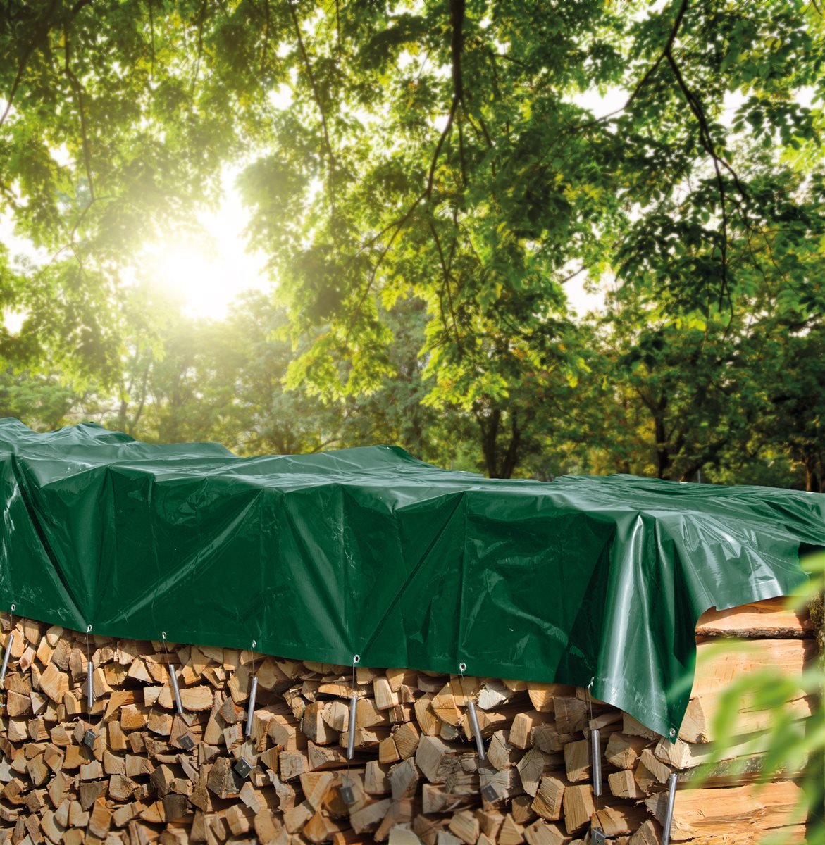 Grüne Prima Holz-Abdeckplane über einem Brennholzstapel im Garten